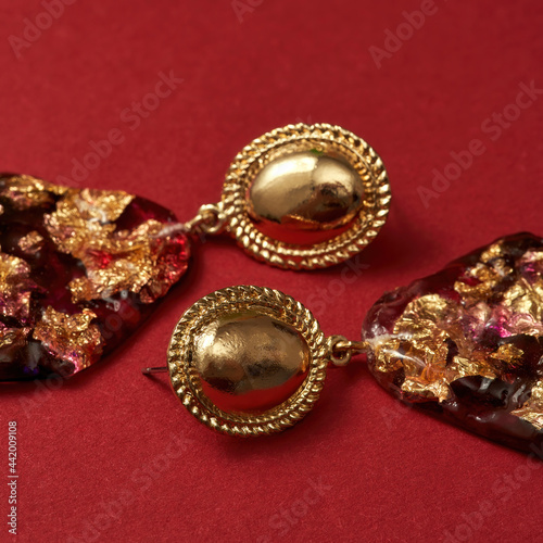 Close up shot of epoxy resin earrings with golden foil inside isolated over red background