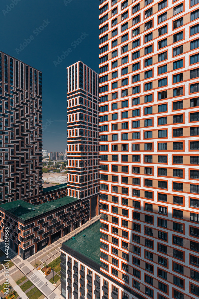 Fototapeta premium A capture in vertical format of a modern residential area with a pedestrian zone and a geometric pattern of paving slabs with green lawns surrounded by tall houses