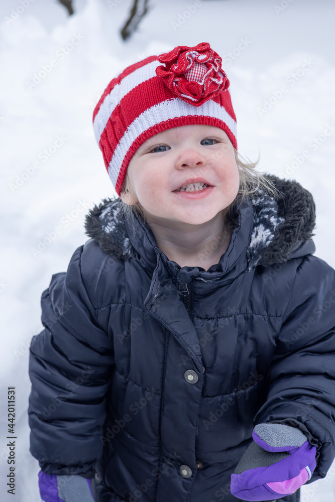 Toddler girl playing in the snow on a cold winter day Toddler girl playing in the snow on a cold winter day