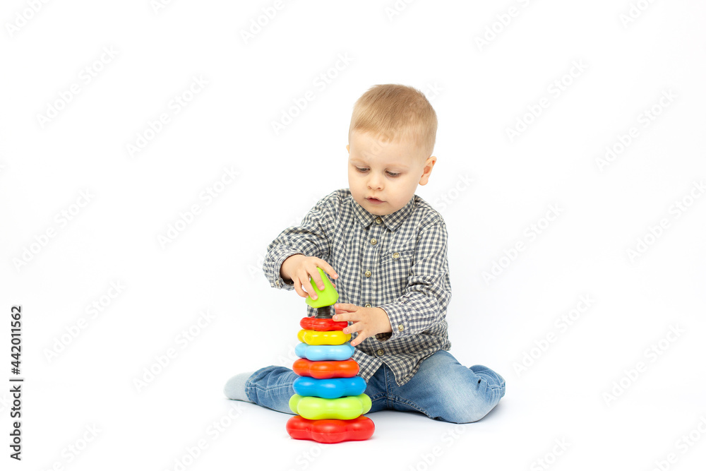 Baby boy on a white background plays in the pyramid. On white background with copy space.Cute boy playing, educational process Baby boy on a white background plays in the pyramid. On white background with copy space.Cute boy playing, educational process