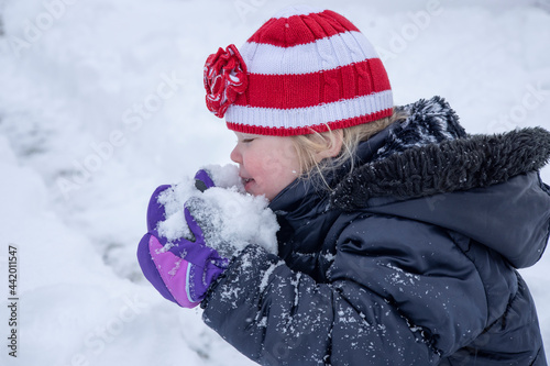 Toddler girl playing in the snow on a cold winter day