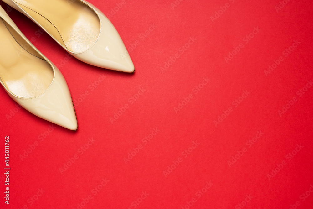 Classic beige patent leather court shoes noses on red background with copy space. Classic beige patent leather court shoes noses on red background with copy space.