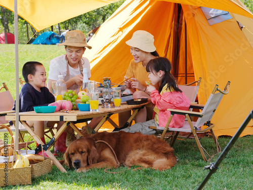 Happy family of four and pet dog have a picnic outdoors