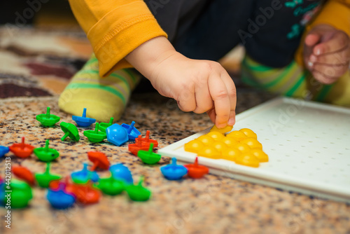 childrens hands laying out colored plastic mosaics