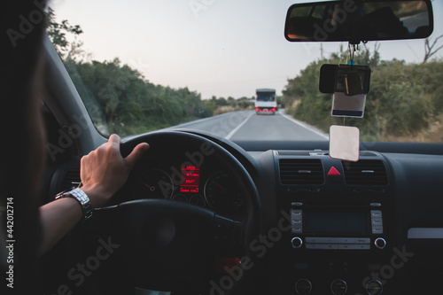 man holding steering wheel with one hand drives on empty road. Driving with one hand is dangerous.