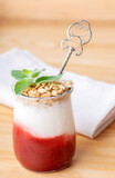 Diet dessert with white yogurt, granola, strawberry jam and green mint leaves decor with cotton napkin on light wooden board. Aquafaba vegan mousse