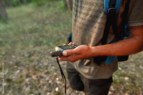 Close up of young male tourist determining location using GPS navigator while standing in the woods