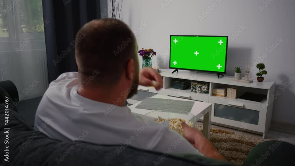 Man Watching Green Screen TV Chroma Key. Back View of a Middle Aged Man Sitting on a Couch Relaxing Living Room on Tv. Man Watching Green Screen TV Chroma Key. Back View of a Middle Aged Man Sitting on a Couch Relaxing Living Room on Tv.