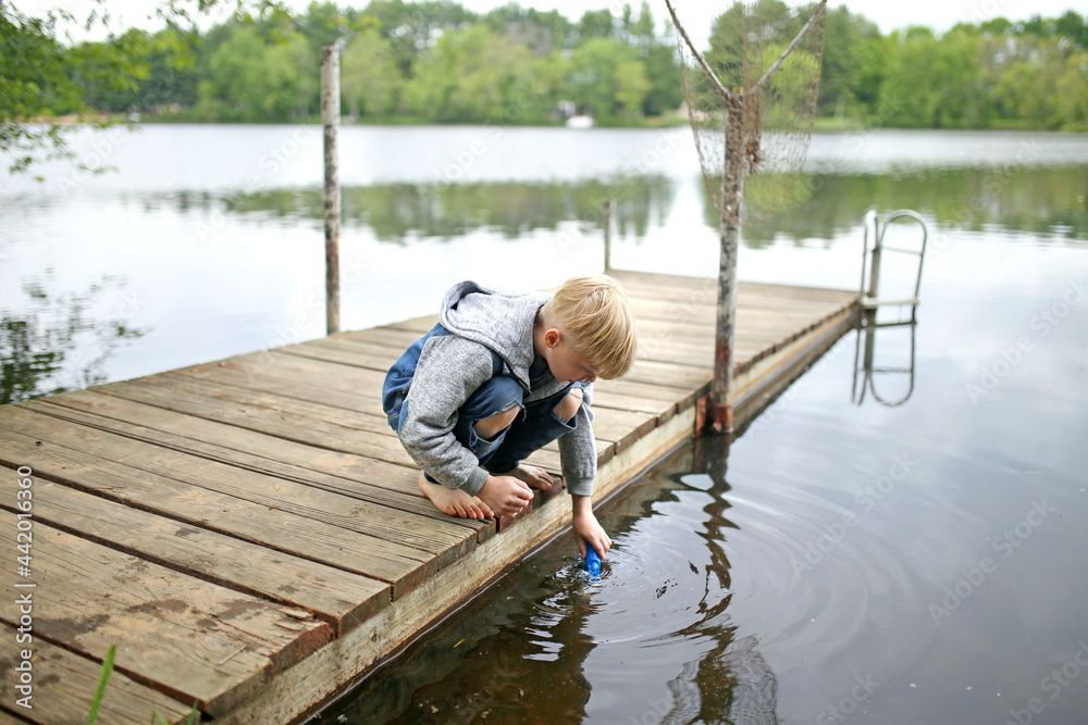 Little Boy Playing in the Water of Lake off Dock Little Boy Playing in the Water of Lake off Dock