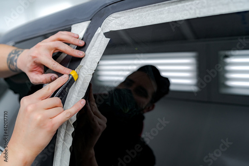 Male mechanic sticking tape on car in repair service photo