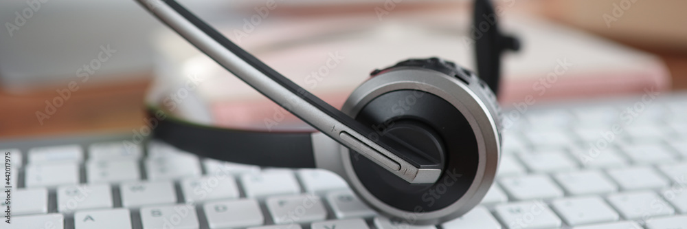 Black headset lying on computer keyboard closeup Black headset lying on computer keyboard closeup