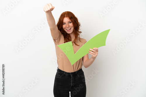 Teenager redhead girl isolated on white background holding a check icon and celebrating a victory