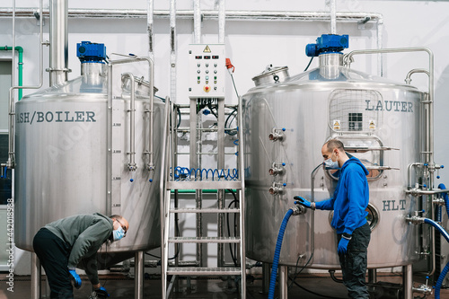 Workers interacting near lauter tun in brewery