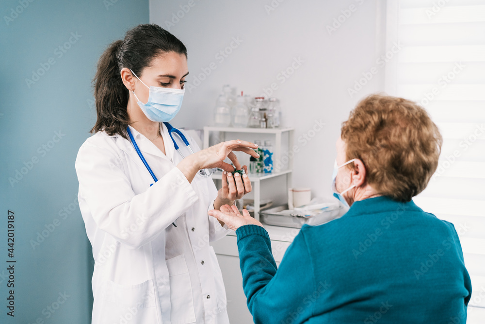 Physician with capsules against unrecognizable senior patient in hospital Physician with capsules against unrecognizable senior patient in hospital