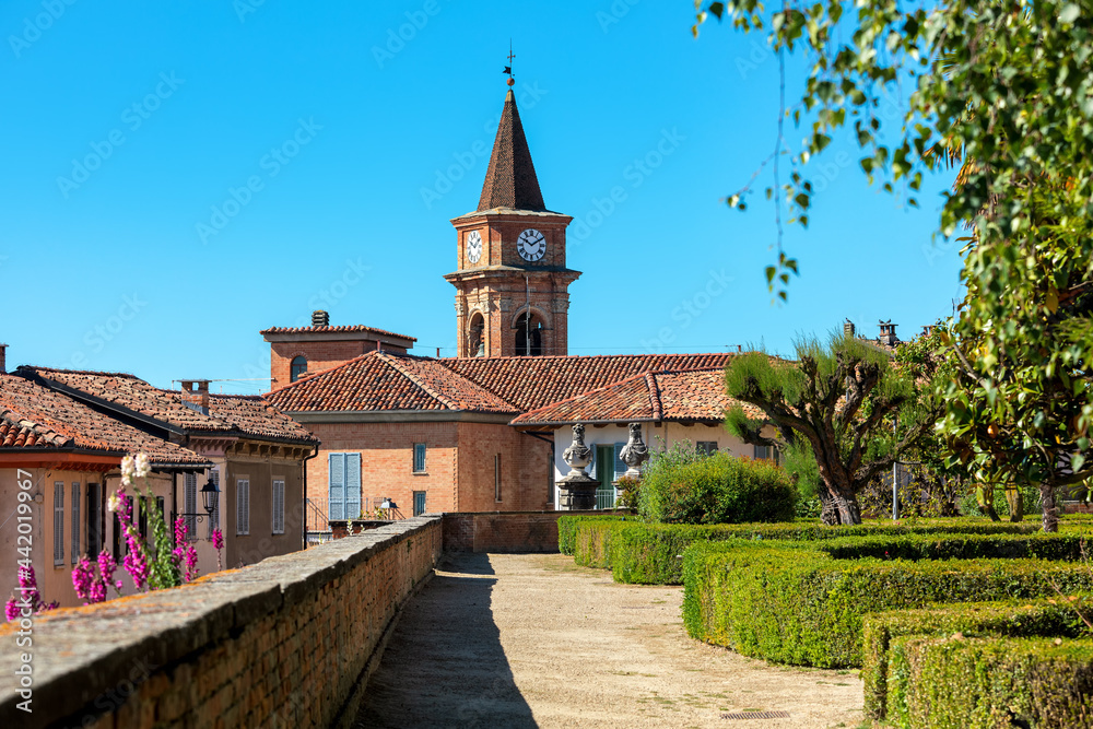 Fototapeta premium Old houses, park and belfry under blue sky in Govone, Italy.