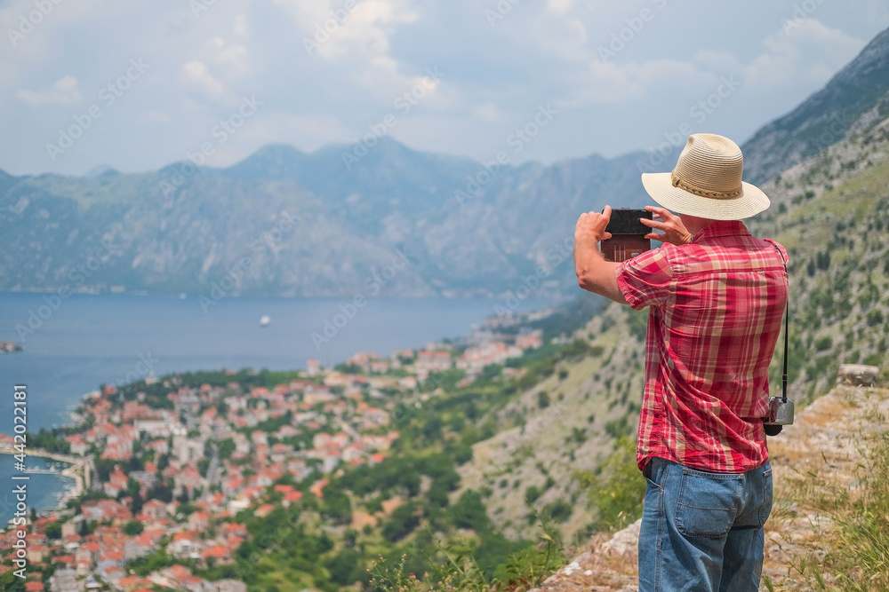 Man stands the beautiful nature landscape and makes photos on smartphone , Montenegro.