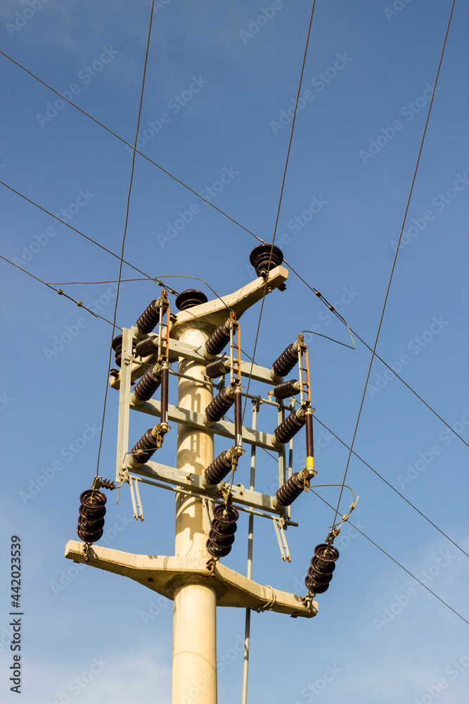 A concrete electric pole with steel cables in blue sky, vertical image A concrete electric pole with steel cables in blue sky, vertical image