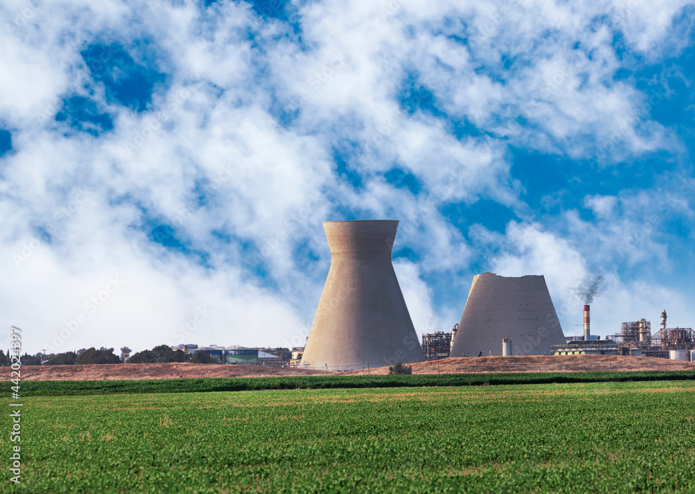 The upper part of the eastern inactive cooling tower in Haifa Oil Refineries had collapsed on June 12th, 2020. Both towers are on the conservation list. large Industrial towers against green fields