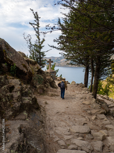 Person walking in a religious hike trail in nature in moon lagoon in lake titicaca peru and bolivia
