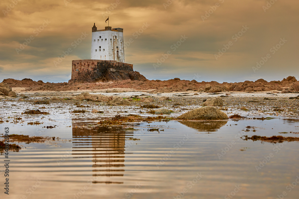 Image of Seymour Tower with cloudy sky and reflection in pool with ripples. Jersey, Channel Islands. Selective focus