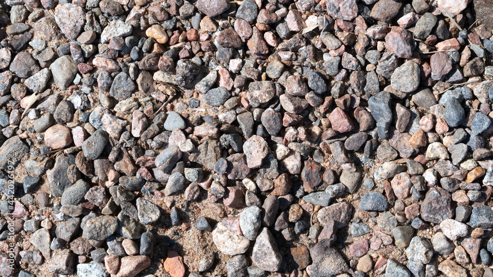 Multicolored stones and gravel on wet river sand. Abstract background texture. Colorful river pebbles, top view Small stone texture for background. Selective focus. Multicolored stones and gravel on wet river sand. Abstract background texture. Colorful river pebbles, top view Small stone texture for background. Selective focus.