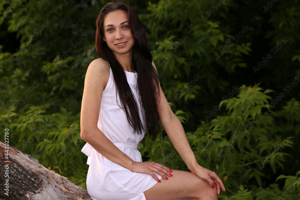 Beautiful woman in white dress sitting on a snag in the lake Beautiful woman in white dress sitting on a snag in the lake