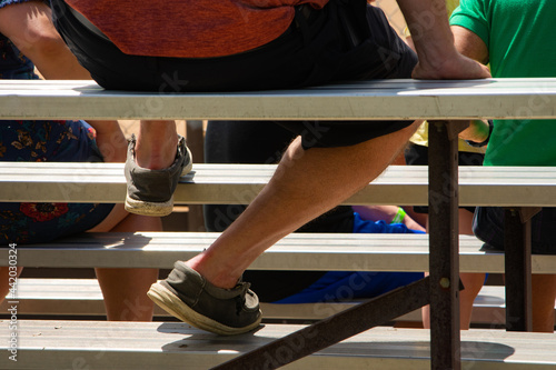 Person sitting on bleachers enjoying ballgame on warm sunny summer day. photo