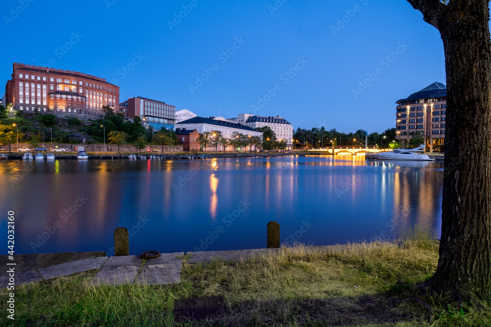 Naklejka premium Night city skyline of an old European city with a bay of water. Citylights casting reflections on the water.