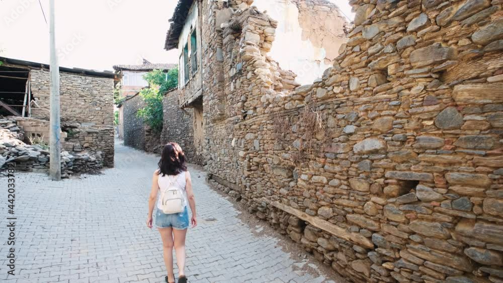 Tourist woman is walking around in Birgi village of Ödemiş district of Izmir, looking at their historical houses. Tourist woman is walking around in Birgi village of Ödemiş district of Izmir, looking at their historical houses.