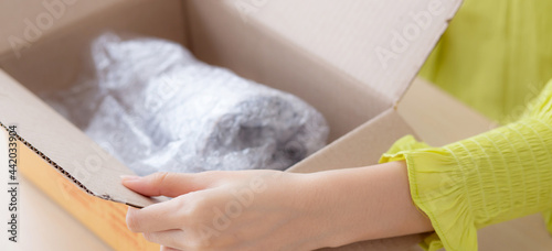 Closeup hand of woman opening parcel box with check product at home, female unpack with knife, delivery and shipping, shipment and express for shop, online shopping store and service concept.