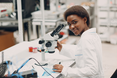 Color woman in tech. Scientist african american woman working in laboratory with electronic tech instruments and microscope.