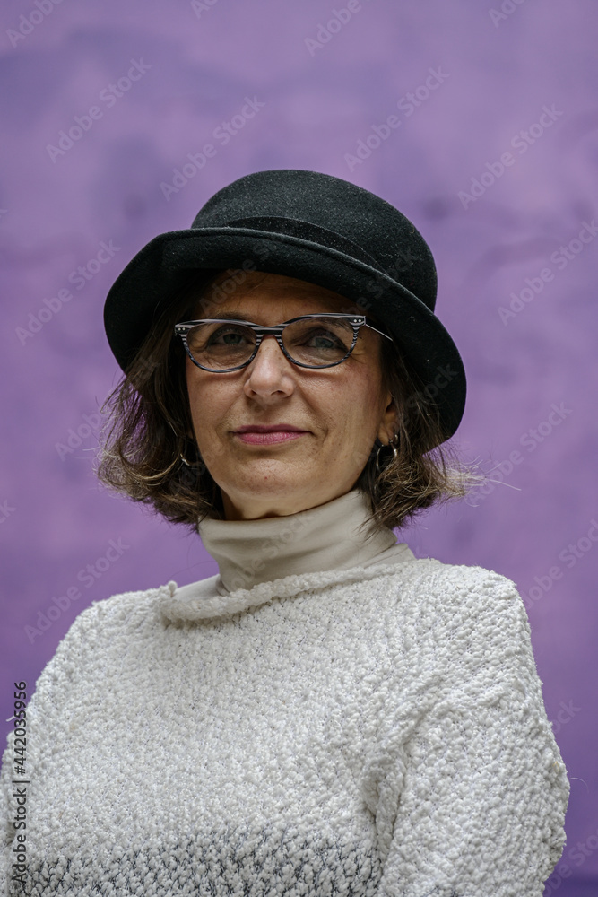 Woman in her sixties with hat, on a purple background Woman in her sixties with hat, on a purple background