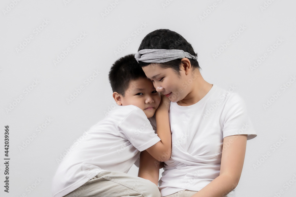 Young adult female cancer patient spending time with little son on gray background. Cancer and family support concept. Young adult female cancer patient spending time with little son on gray background. Cancer and family support concept.