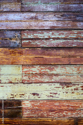 Texture, old grungy paint-striped wood slatted wall covered with peeling paint.