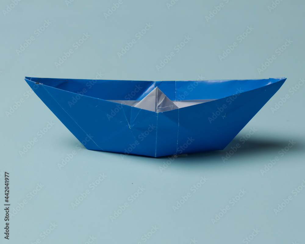 Blue boat-shaped origami on a blue background. Playing origami helps improve thinking power and increase children's creative abilities. Playing origami can be an alternative learning for children.