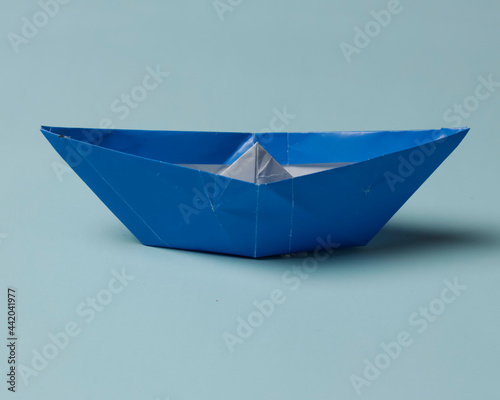 Blue boat-shaped origami on a blue background. Playing origami helps improve thinking power and increase children's creative abilities. Playing origami can be an alternative learning for children. © AndhikaRaya