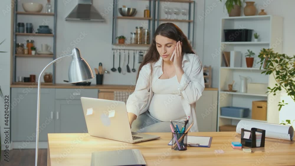 Young Pregnant Woman Working on Laptop at Home in Living Room. Concept of Remote Work, Distance Learning, Work During Pregnancy and Freelancing. Young Pregnant Woman Working on Laptop at Home in Living Room. Concept of Remote Work, Distance Learning, Work During Pregnancy and Freelancing.
