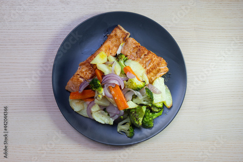 A plate of grilled salmon with vegetables on the side.
