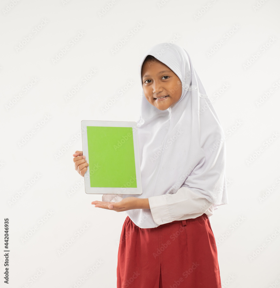 a girl wearing a hooded elementary school uniform stands holding a digital tablet and showing the tablet screen to the camera with an isolated background a girl wearing a hooded elementary school uniform stands holding a digital tablet and showing the tablet screen to the camera with an isolated background