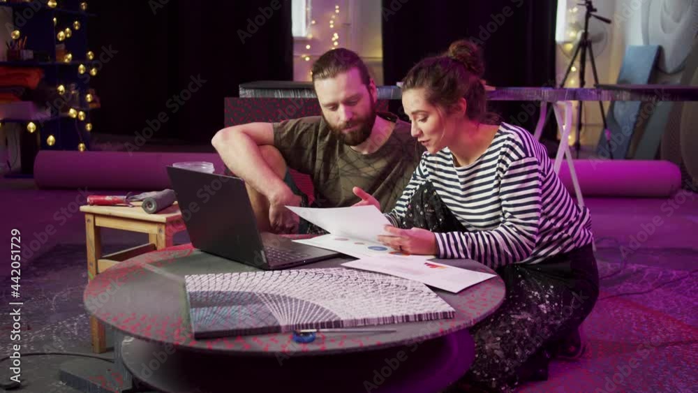 Two painters are looking through documents and searching on the Internet 