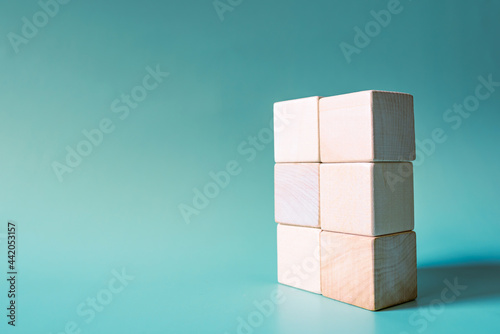 A stack of six wooden cubes on a light blue background. Mockup, copy space. Concept business picture.