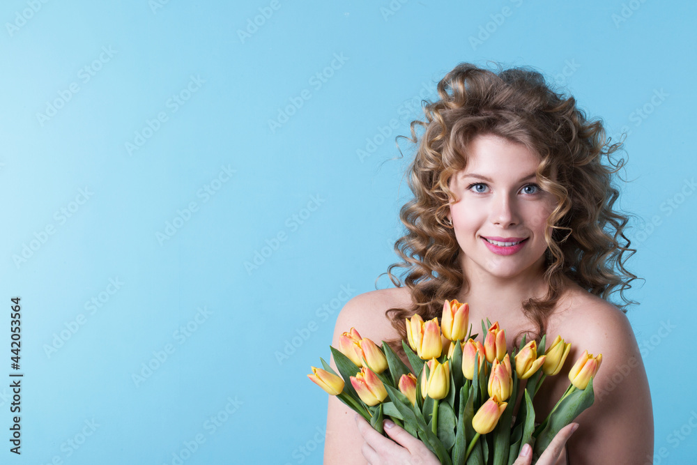 Portrait of a pretty curly woman smiling with tulips. Happiness and holiday