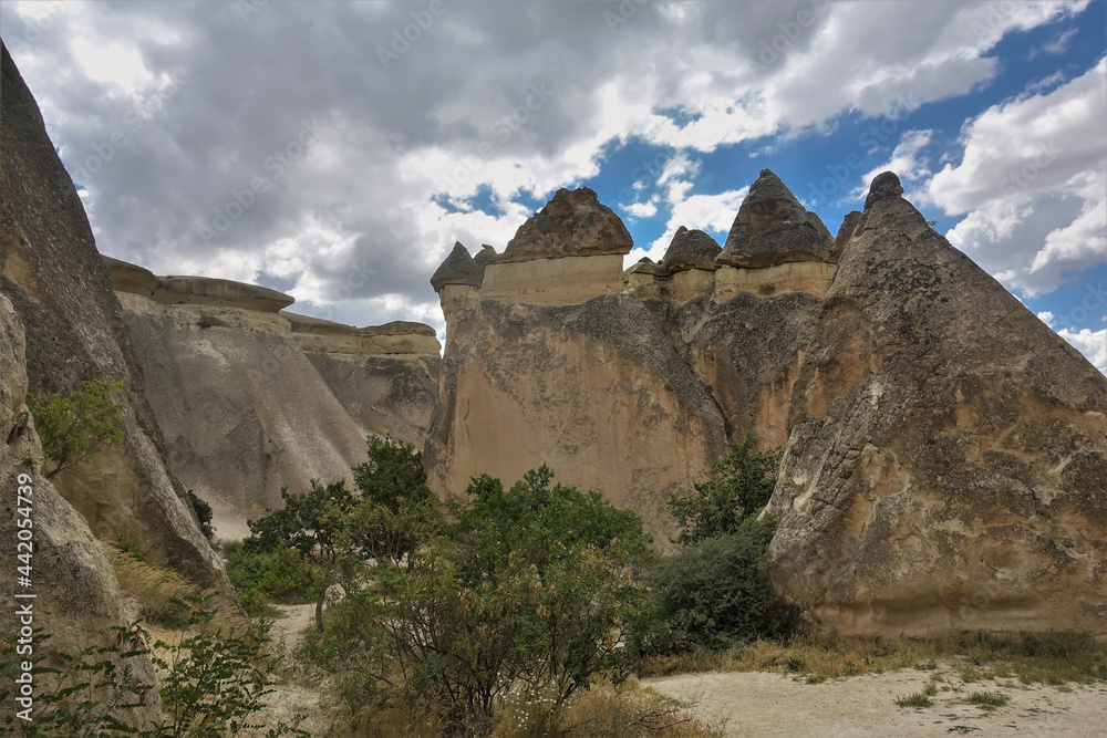 Strange mountains of Cappadocia against the blue sky with clouds. Amazing conical rocks with sharp mushroom-like peaks. Tuff and basalt. Turkey