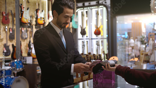 An upwardly mobile Muslim man using smart payment to pay for a product at a sale terminal with nfc identification payment for verification and authentication