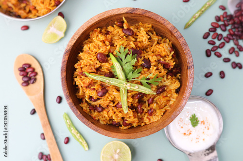 Indian cuisine - Kidney Beans Biryani, Rajma Pulao. Garnished with chopped coriander, and lemon wedges. Rajma biryani served with dahi. Along with copy space. Rajma Chawal flatlay.