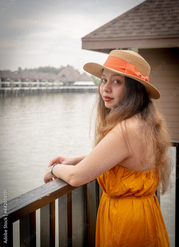 Girl with beautiful long hair wearing an orange dress and a straw hat ...