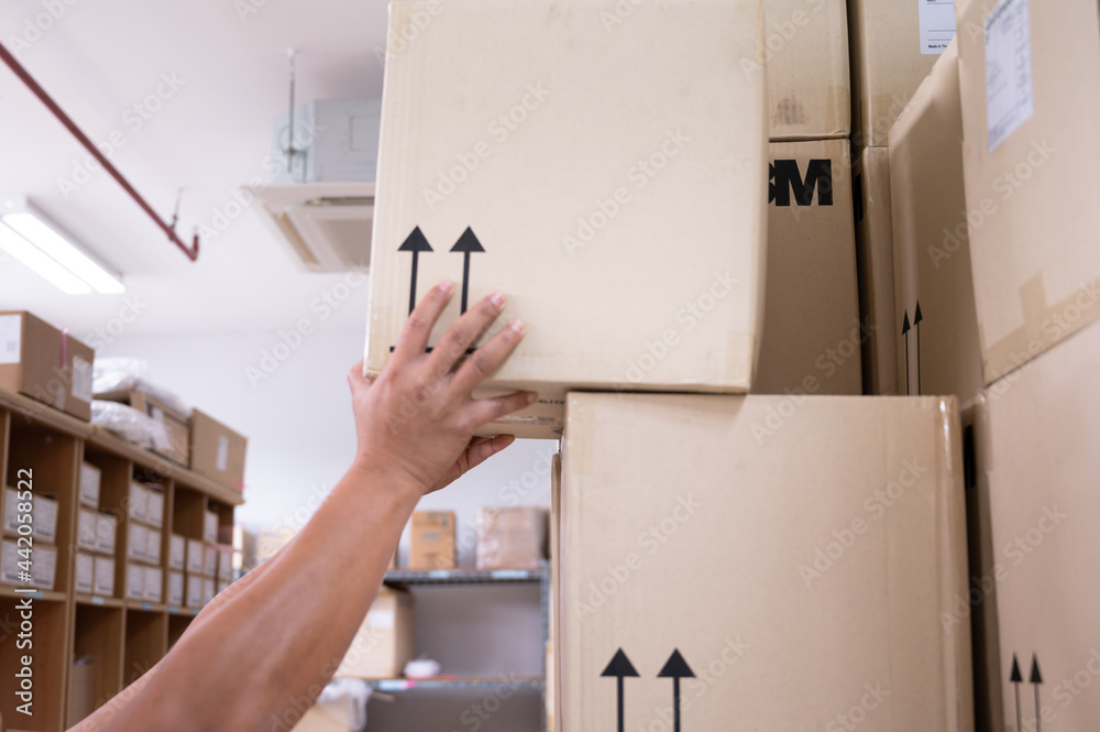 Close up hands of warehouse worker lifting box in storage room.Man ...
