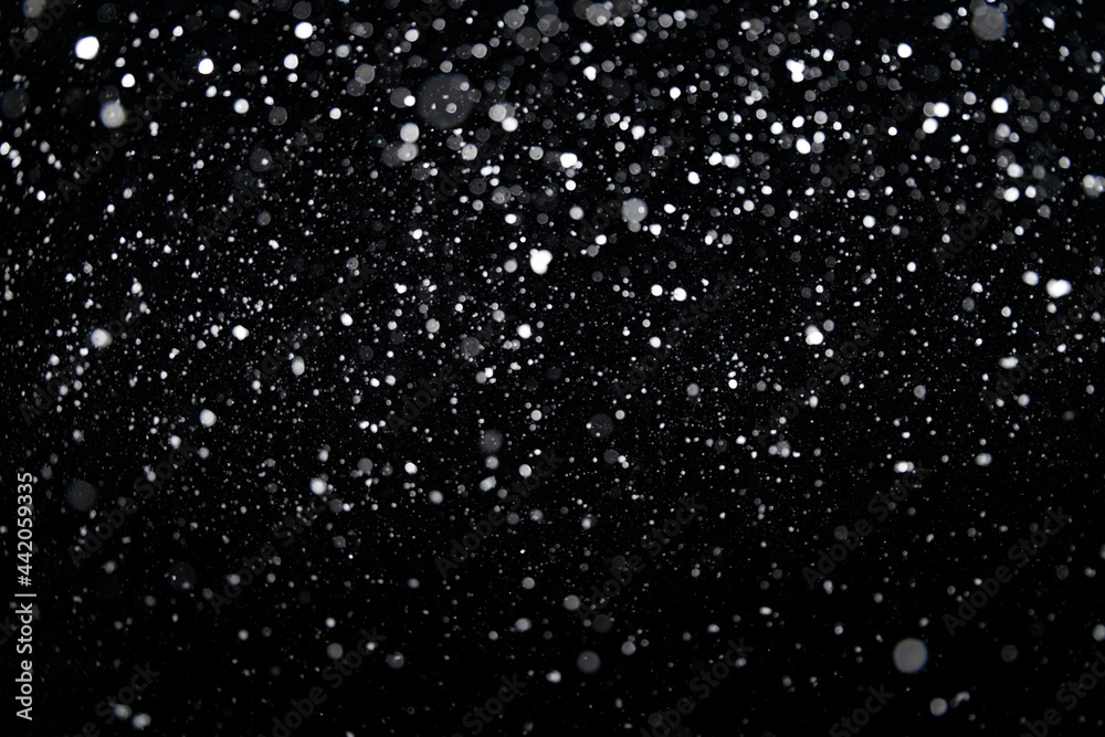 Many snowflakes in blur on black background. Snowfall layer for winter project
