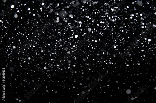 Many snowflakes in blur on black background. Snowfall layer for winter project