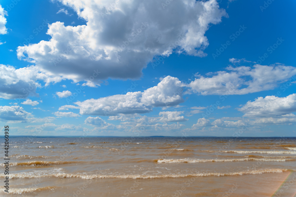 The sea shore, waves on the water and clouds in the sky